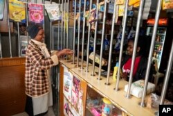 Linnah Mueni, left, buys a bag of maize flour from a small shop in Kitengela, on the outskirts of the capital Nairobi, Kenya, April 17, 2023.