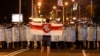 FILE - A protester holds an old Belarusian national flag as he stands in front of police line during a rally after the Belarusian presidential election in Minsk, Belarus, Aug. 9, 2020.