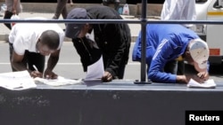 FILE -Abadabuka eZimbabwe abadinga amaphepha okuhlala lokusebenza kwele South Africa.