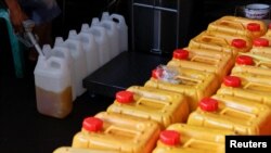 A worker fills jerrycans with cooking oil at a distribution station in Jakarta, Indonesia, May 20, 2022. REUTERS/Willy Kurniawan