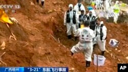 In this image taken from video footage run by China's CCTV, search-and-rescue workers stand at the area where they recovered the second orange-colored "black box" at the China Eastern flight crash site in Tengxian County, March 27, 2022, in southern China