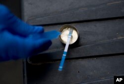 FILE - A volunteer from the Intercambios Puerto Rico needle exchange program tests a user's heroin for fentanyl, in an area popular with drug users behind an abandoned home in Humacao, Puerto Rico, Dec. 14, 2018.