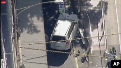 In this photo made video from the Australian Broadcasting Corp., a white SUV vehicle is stopped after allegedly striking pedestrians, Dec. 21, 20217, in Melbourne, Australia. Local media say over a dozen people have been injured after a car drove into ped