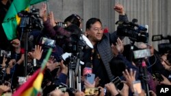 Presiden Bolivia Luis Arce mengepalkan tangan dikelilingi oleh para pendukung dan media, di luar istana pemerintah di ibu kota La Paz, pasca upaya kudeta yang gagal (26/6). 