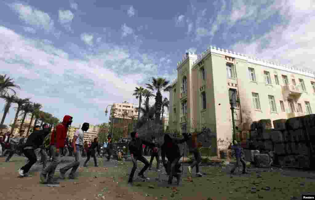 Protesters opposing Egyptian President Mohamed Morsi throw stones towards riot police during clashes near Tahrir Square, Cairo, Egypt, January 25, 2013. 