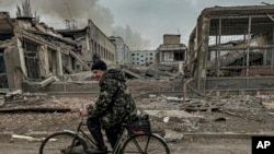 A man rides on a bike in front of the mail office which was destroyed by a Russian airstrike in Kurakhove, Donetsk region, Ukraine, Nov. 7, 2024. 