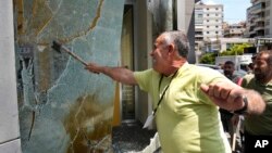Seorang nasabah yang marah memecahkan jendela di cabang Bank Byblos selama aksi protes menuntut pencairan dana tabungan para deposan, di Beirut, Lebanon, Kamis, 15 Juni 2023.
