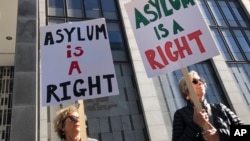 ARCHIVO - Manifestantes sostienen carteles en inglés que dicen "El asilo es un derecho" afuera del Tribunal Federal de San Francisco, el 24 de julio de 2019, en San Francisco, EEUU.
