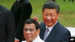 FILE - Chinese President Xi Jinping and Philippine President Rodrigo Duterte wave to the media following a welcome ceremony at Malacanang Palace in Manila, Philippines, Nov. 20, 2018. 