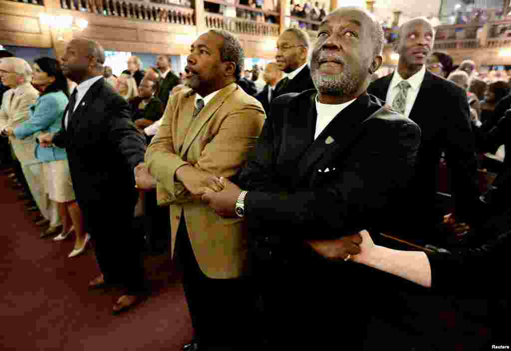 Kasisi Richard Harkness akishikana mkono na Kasisi Jack Lewin (2ndR) wanapoimba wimbo wa &quot;We Shall Overcome&quot; mwishoni mwa sala ya makumbusho katika kanisa la Morris Brown AME, Charleston, South Carolina, June 18, 2015.