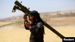 FILE - An Islamist Syrian rebel group Jabhat al-Nusra fighter talks on a walkie-talkie while carrying his weapon in the northern Idlib province May 17, 2014. 