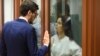 Ksenia Karelina, también conocida como Khavana, habla con su abogado de pie dentro de una jaula de cristal en una sala del tribunal en Ekaterimburgo, Rusia, el jueves 15 de agosto de 2024. 