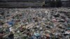 FILE - A man walks on the shores the Arabian Sea, littered with plastic and other garbage in Mumbai, India, June 4, 2018. The theme for that year's World Environment Day, marked on June 5, is "Beat Plastic Pollution." 