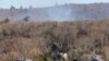 Smoke rises from a wildfire behind a row of lakefront properties in the town of Awosting, as seen from across Greenwood Lake, Lakeside, New Jersey, Nov. 11, 2024.