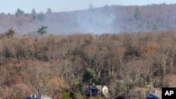 Smoke rises from a wildfire behind a row of lakefront properties in the town of Awosting, as seen from across Greenwood Lake, Lakeside, New Jersey, Nov. 11, 2024.
