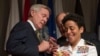 Adm. Michelle Howard, right, lends a hand to Secretary of the Navy Ray Mabus as he and Wayne Cowles, Howard's husband, put four-star shoulder boards on Howard's service white uniform during her promotion ceremony at the Women in Military Service for Ameri