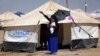 A woman, who fled from violence in Mosul, carries a baby in a camp edging Irbil in Iraq's Kurdistan region June 25, 2014. 