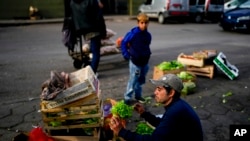 Seorang pedagang tampak memeriksa kondisi seladanya saat ia mengatur barang dagangannya di sebuah pasar buah dan sayuran di Buenos Aires, Argentina, pada 10 Mei 2024. (Foto: AP/Natacha Pisarenko)