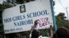 An activist puts a message on the sign board at the main entrance of Moi Girls School Nairobi, a prestigious government boarding school in Nairobi, Kenya, June 4, 2018, during a protest against alleged rape of three girls at the school.