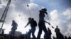 FILE - Palestinian protesters use slingshots to throw stones towards Israeli security forces during clashes following a protest marking the 11th anniversary of the death of late Palestinian leader Yasser Arafat, in the West Bank city of Ramallah, Wednesda