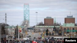 Para pengemudi truk dan para pendukungnya memblokir akses ke Jembatan Ambassador yang menghubungkan Detroit di AS dan Windsor di Kanada dalam demo memprotes aturan wajib vaksinasi COVID-19, di Windsor, Otario, Kanada, 12 Februari 2022. (Foto: Carlos Osorio/Reuters)
