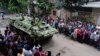 An armored vehicle drives past members of the press after an operation against militants who took hostages at a restaurant popular with foreigners in Dhaka, Bangladesh, Saturday, July 2, 2016.