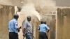An armed policeman carrying a pistol and tear gas patrols while firemen attempt to put out a fire in the Salvation Army Church after it was set on fire by rioting youths, following Friday Muslim prayers in Mombasa, Kenya, Oct. 4, 2013.