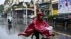 FILE - A woman in a poncho rides a bicycle during heavy rainfall in Hanoi, Oct. 14, 2020, as tropical storm Nangka made landfall in north-central Vietnam. 