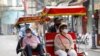 Foreign tourists wear protective masks while traveling on three-wheel cycles along streets in Hanoi, Vietnam, March 17, 2020.